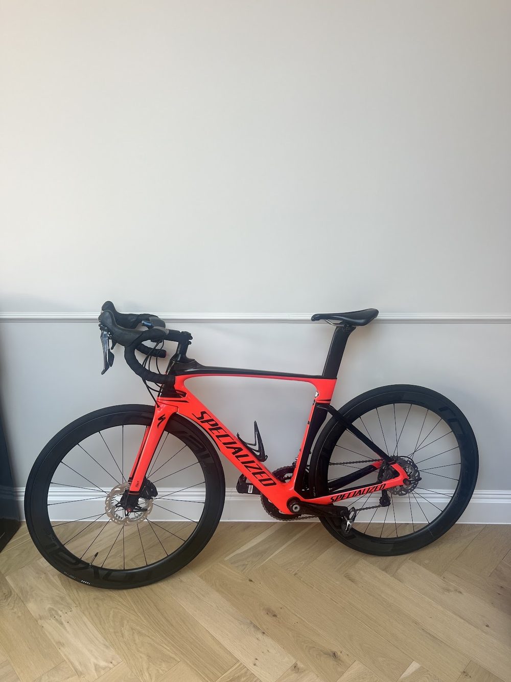 A red and black Specialized Venge aero road bike standing against a plain wall, finished and ready for collection